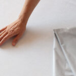 Hand on the bed next to the waterproof sex blanket depicting that there is no leak