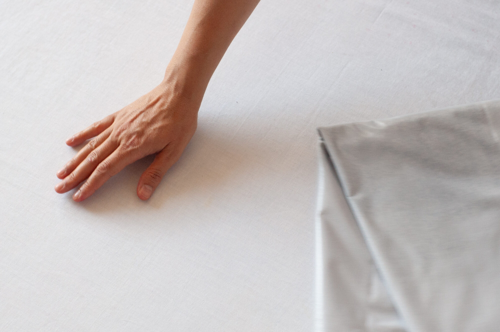 Hand on the bed next to the waterproof sex blanket depicting that there is no leak