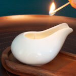 Lighting a massage candle kept on a beautiful wooden plate
