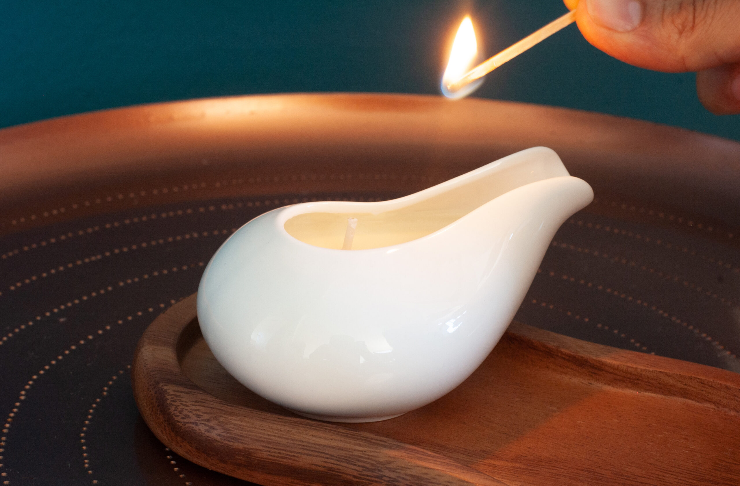 Lighting a massage candle kept on a beautiful wooden plate