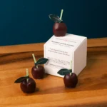 Cute maroon cherry candles kept on the box of candles. It is very small set of candles