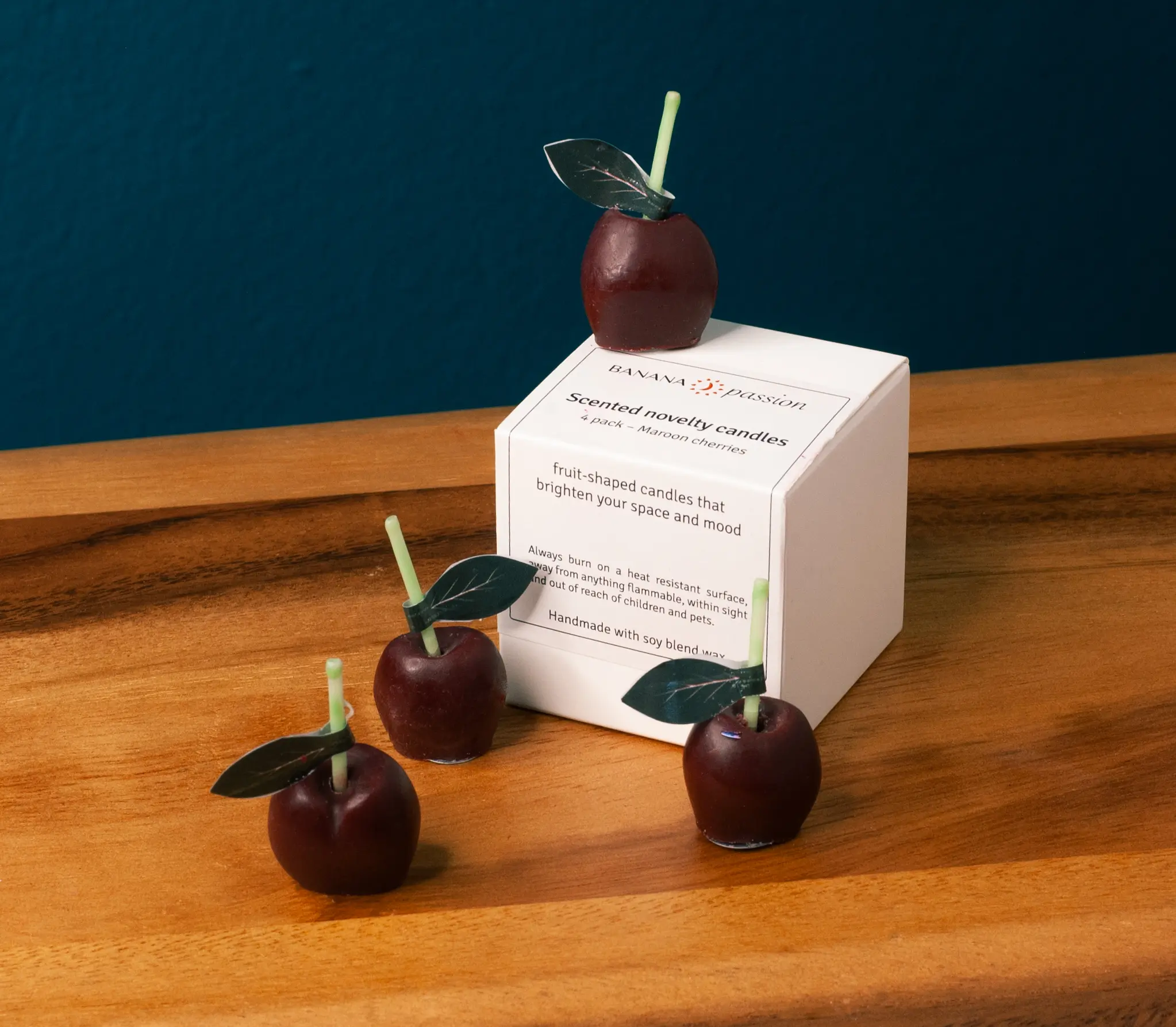 Cute maroon cherry candles kept on the box of candles. It is very small set of candles