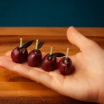 Cute maroon cherry candles held by a woman on her palm to show how big these candles are