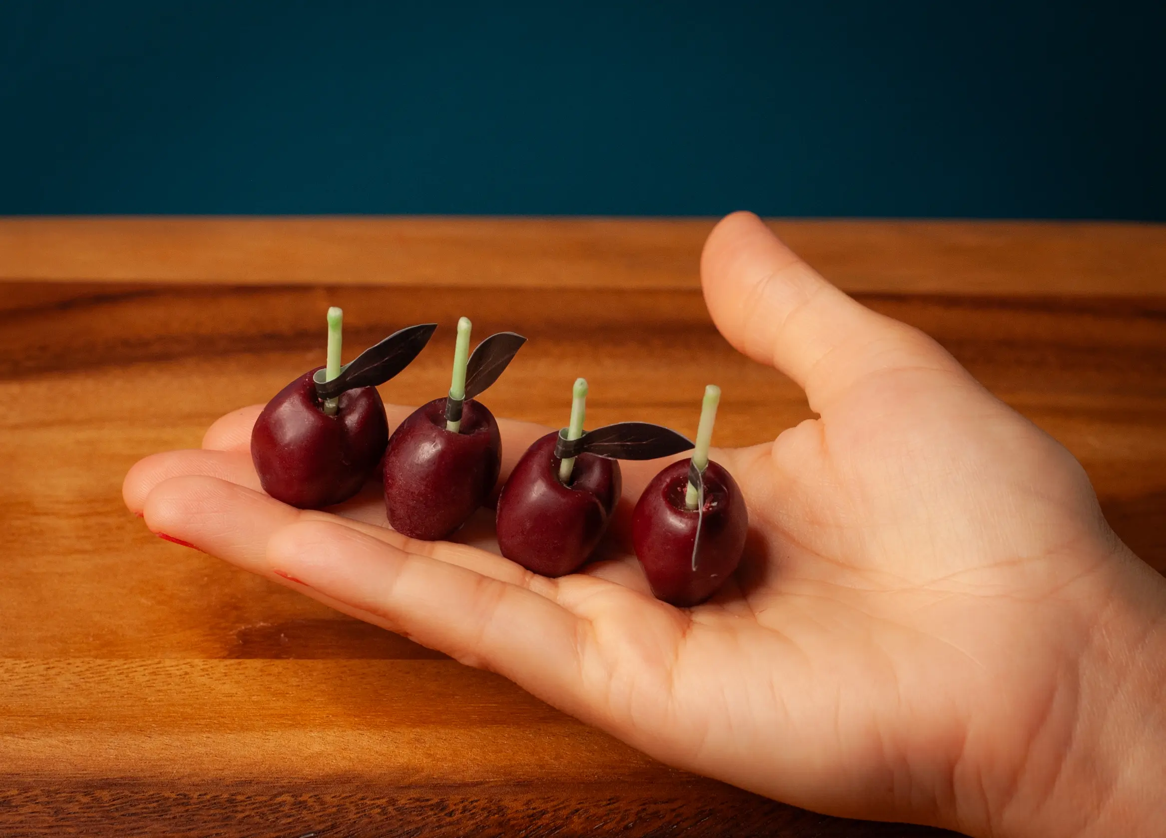 Cute maroon cherry candles held by a woman on her palm to show how big these candles are