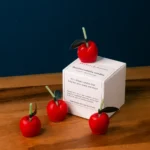 Cute red cherry candles kept on the box of candles. It is very small set of candles