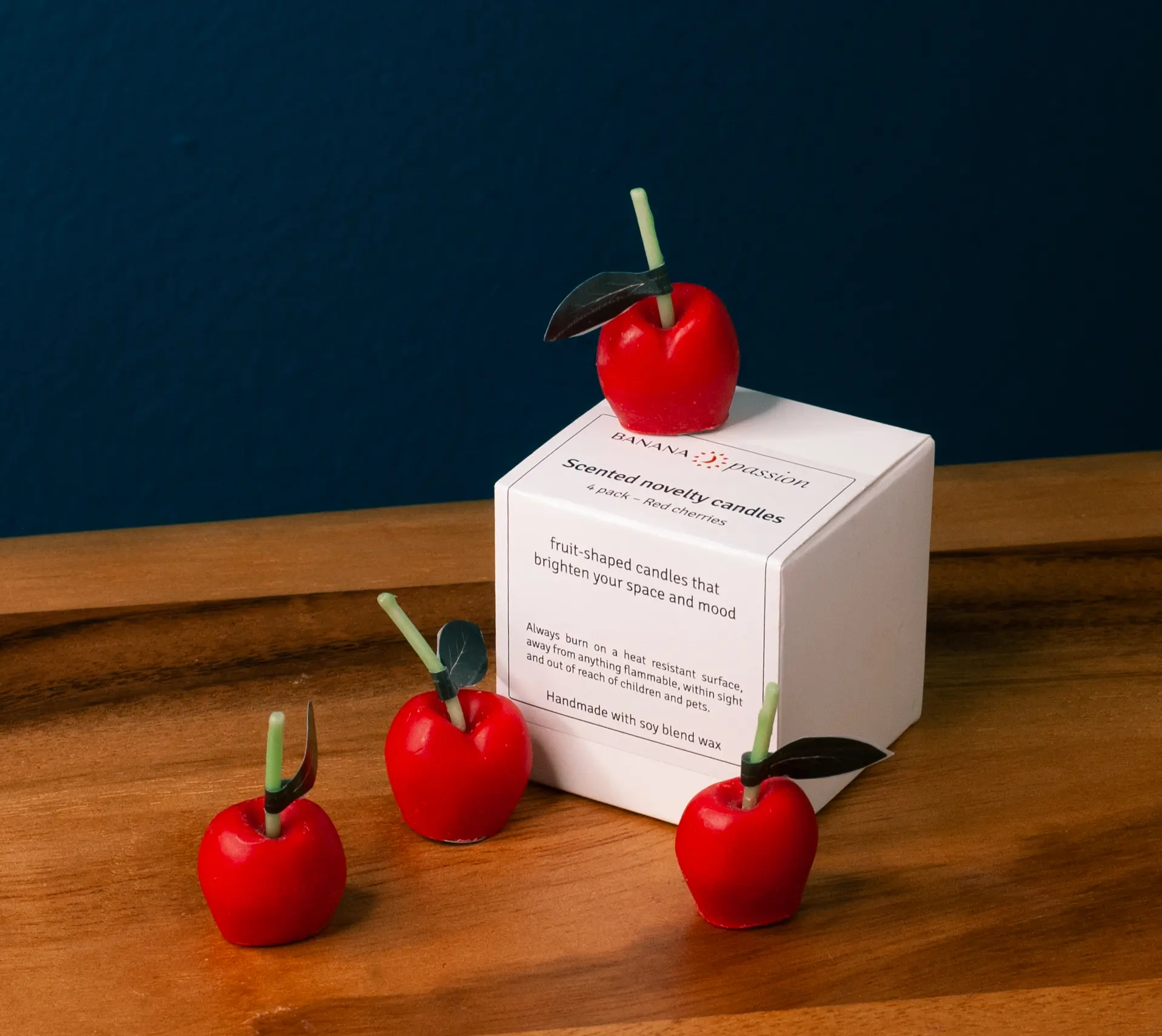 Cute red cherry candles kept on the box of candles. It is very small set of candles