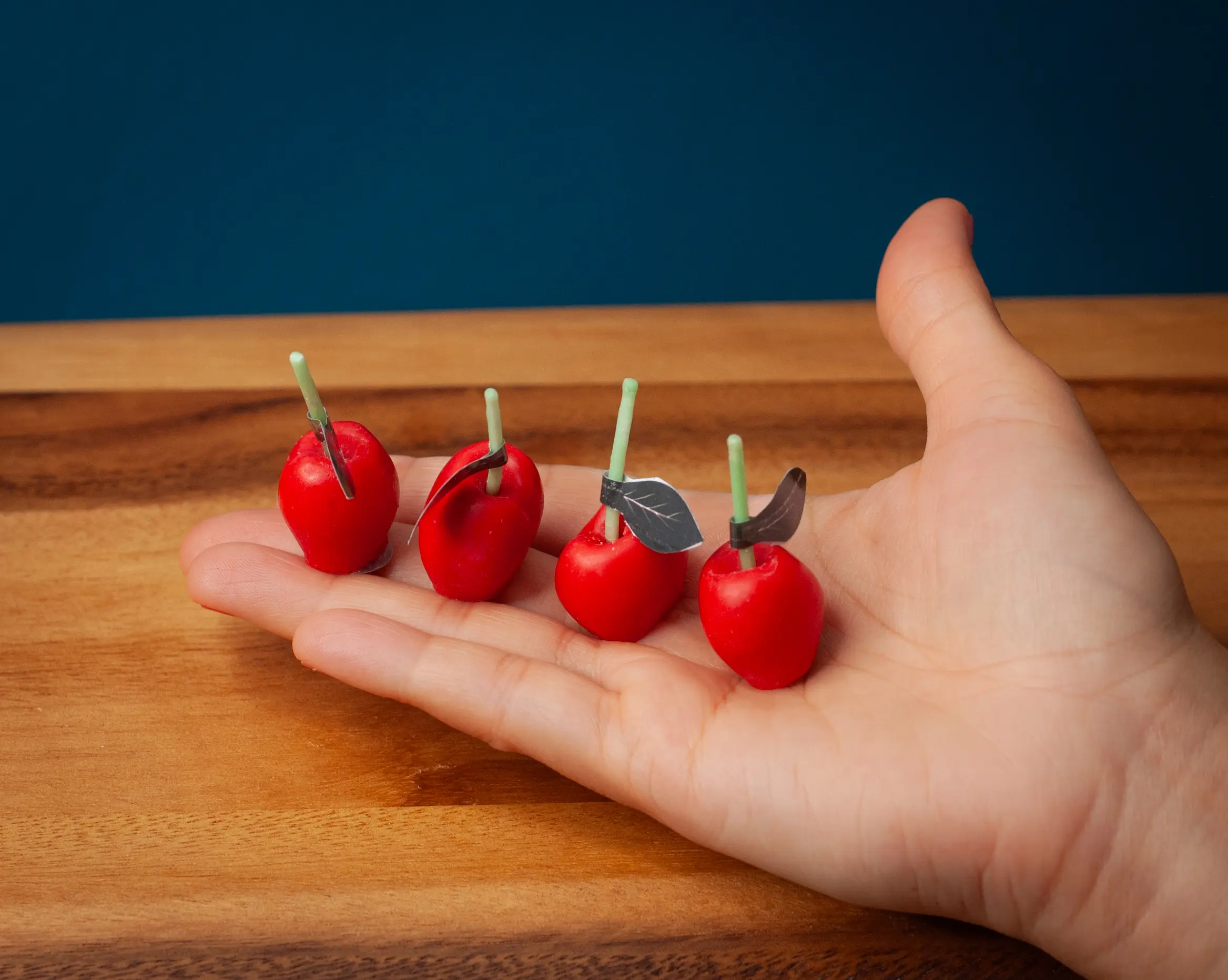 Cute red cherry candles held by a woman on her palm to show how big these candles are