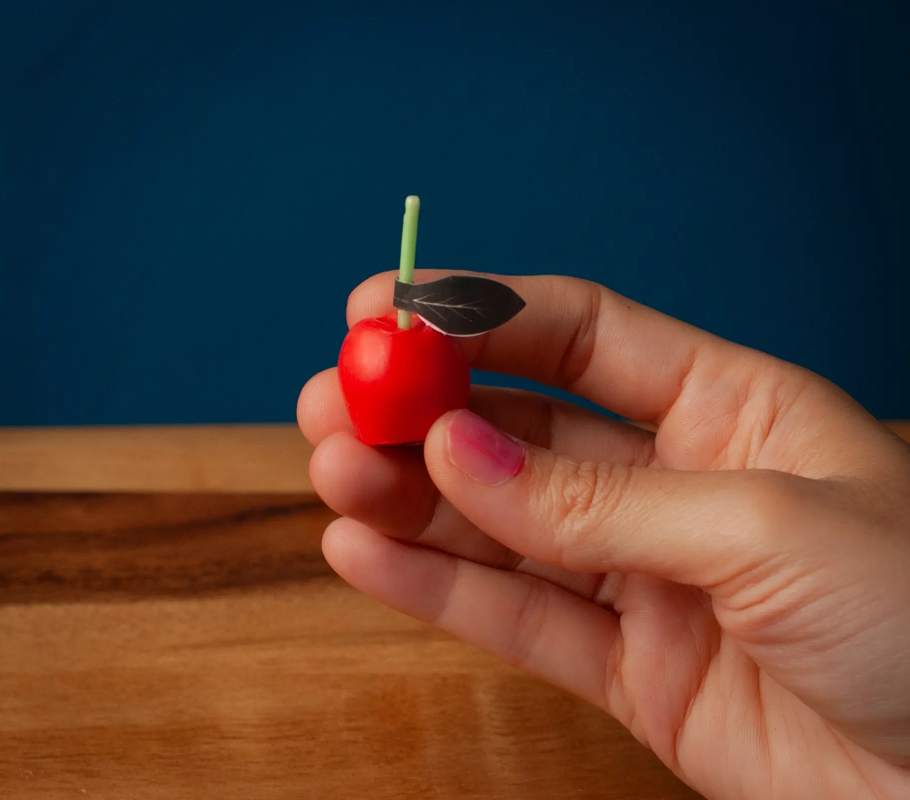 Cute red cherry candle held by a woman in her hands
