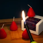 Strawberry shaped candles being lit by a woman. These strawberry candles look like a strawberry and smell like a strawberry fruit.