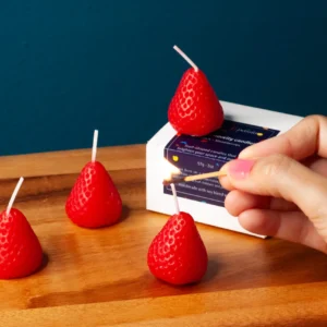 Strawberry shaped candles being lit by a woman. These strawberry candles look like a strawberry and smell like a strawberry fruit.