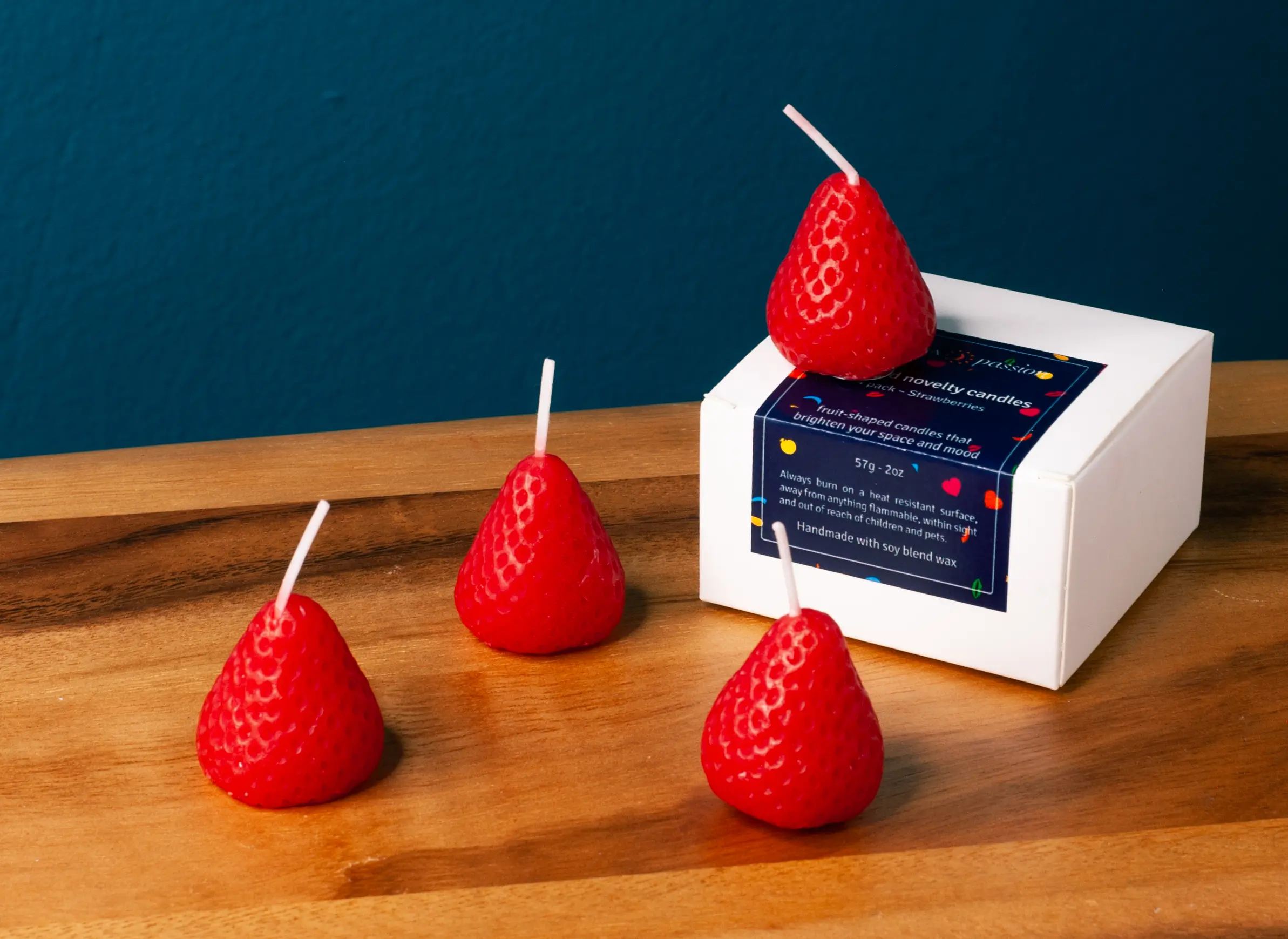 Strawberry shaped candles being lit by a woman. These strawberry candles look like a strawberry and smell like a strawberry fruit.