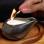 A woman's hand showing that she lights a massage candle.