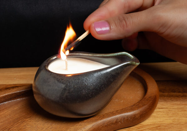 A woman's hand showing that she lights a massage candle.