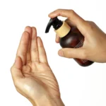 Massage oil being sprayed on another hand of a woman.