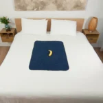 Navy blue sex blanket on top of the bed with a banana for scale. This is a perfect waterproof blanket for going solo or perfect travel waterproof blanket.