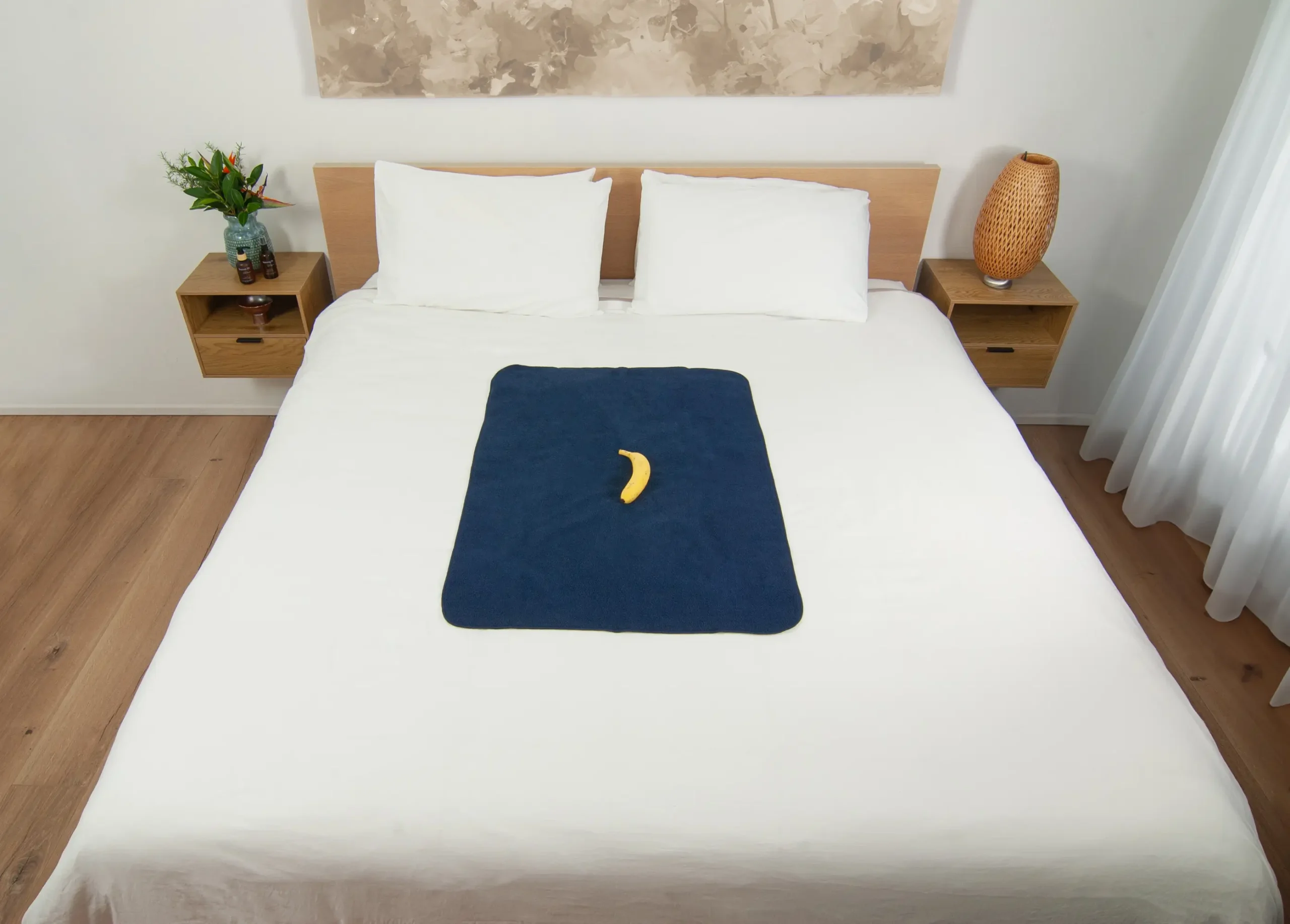 Navy blue sex blanket on top of the bed with a banana for scale. This is a perfect waterproof blanket for going solo or perfect travel waterproof blanket.