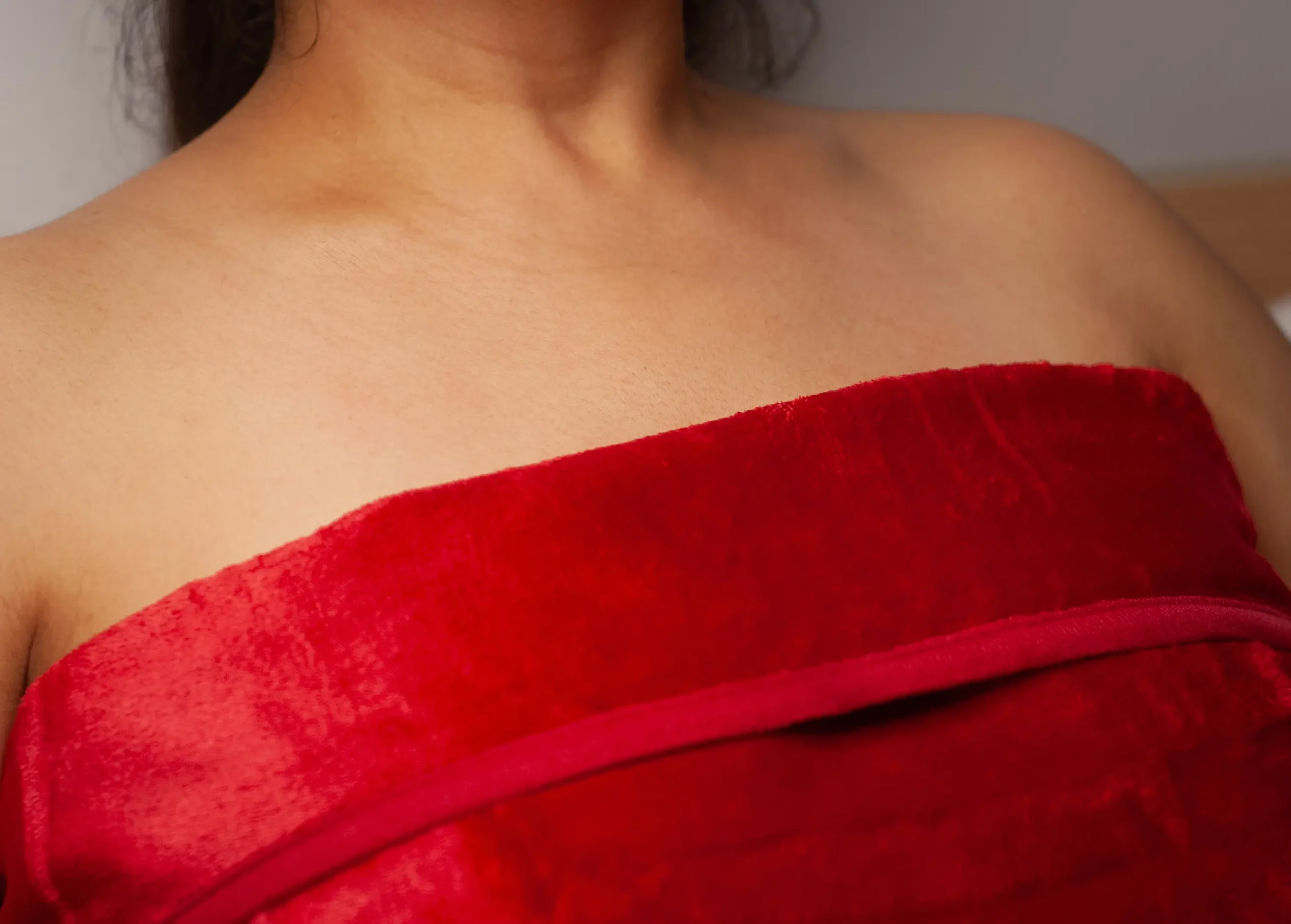 Passion Red intimacy blanket been worn by a woman who has dark black hair. She is wearing this red waterproof blanket in a sensual way.