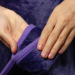Purple Waterproof Blanket in the hands of a woman showcasing it is soft. This is exactly like splash blanket or liberator throw. Best squirt blanket.
