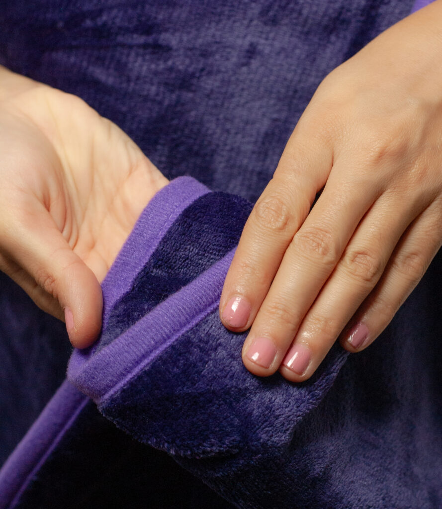 Purple Waterproof Blanket in the hands of a woman showcasing it is soft. This is exactly like splash blanket or liberator throw. Best squirt blanket.