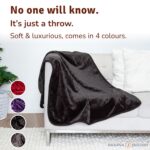 Black velvety waterproof throw on a sofa, soft leakproof couch blanket that protects from spills, pets and messy intimacy while looking like a normal cosy throw.