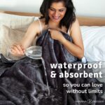 Dark grey waterproof blanket with water being poured onto the surface to show it stays dry underneath.