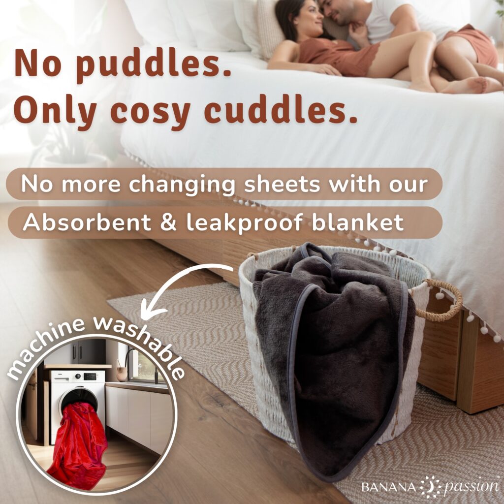 Couple cuddling on a bed above the words “No puddles, only cosy cuddles,” with a folded Banana Passion velvety waterproof blanket in a basket and an inset image showing the waterproof intimacy blanket going into a washing machine, highlighting that it is absorbent, leakproof and machine washable.