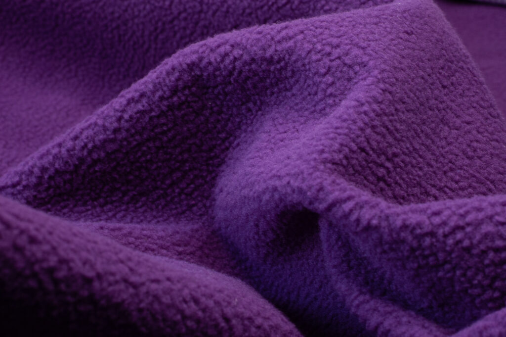 Close-up of the polar fleece of waterproof sex blanket in dark purple, showing the soft fabric.