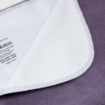 Waterproof blanket shown partially flipped over with backside film visible.