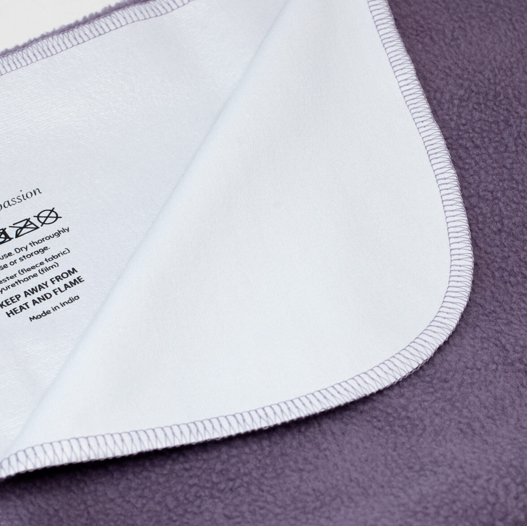 Waterproof blanket shown partially flipped over with backside film visible.