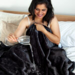 Purple Waterproof Blanket in the hands of a woman showcasing it is soft. This is exactly like squirt blanket or liberator throw. Best squirt blanket.