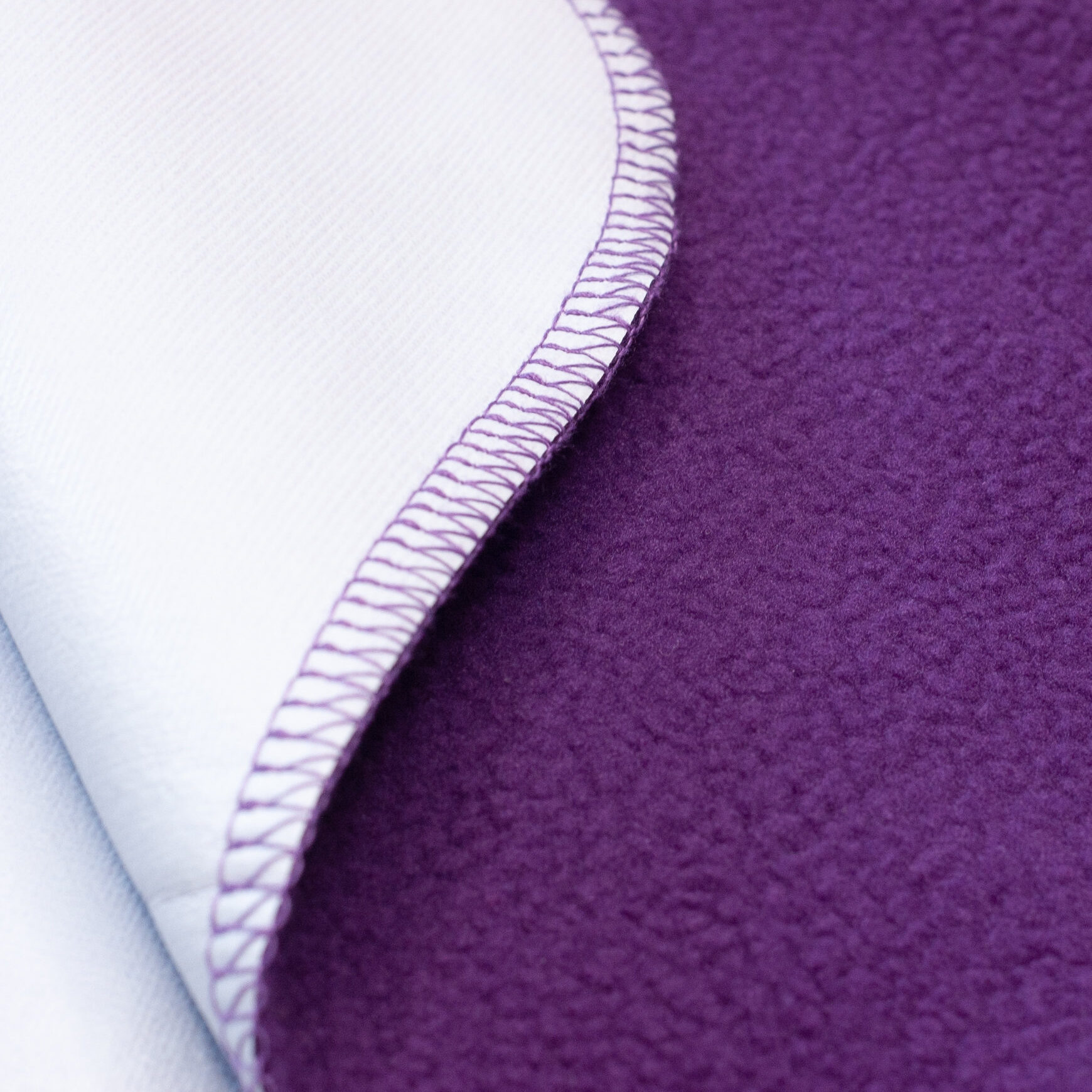 Close-up of a polar fleece waterproof blanket, showing the soft top layer and the shiny waterproof film on the folded edge.