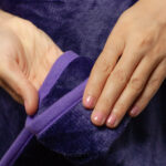 Purple Waterproof Blanket in the hands of a woman showcasing it is soft. This is exactly like splash blanket or liberator throw. Best squirt blanket.