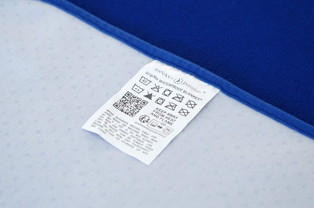 GripMe waterproof blanket care label close-up with washing instructions
