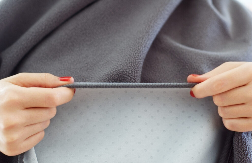 GripMe waterproof blanket shown edge on, with soft polar fleece shown on the upper half and silicon dots lining the underside fabric.