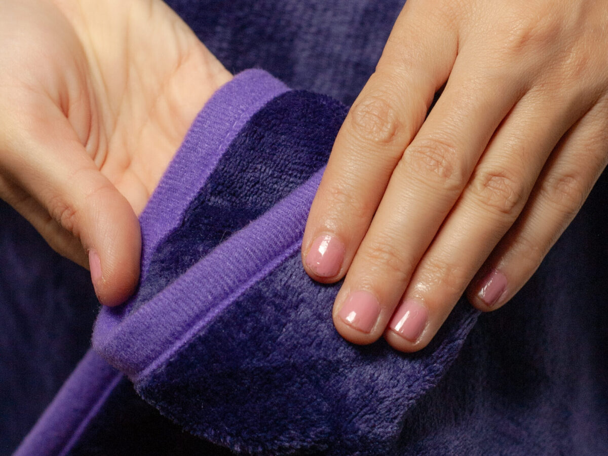 Purple Waterproof Blanket in the hands of a woman showcasing it is soft. This is exactly like squirt blanket or liberator throw. Best squirt blanket.