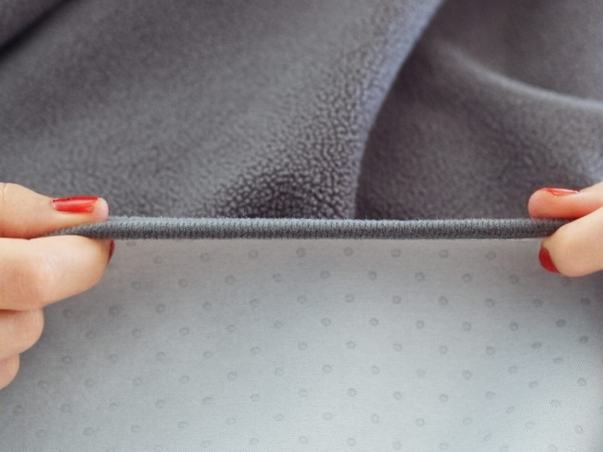 GripMe waterproof blanket shown edge on, with soft polar fleece shown on the upper half and silicon dots lining the underside fabric.