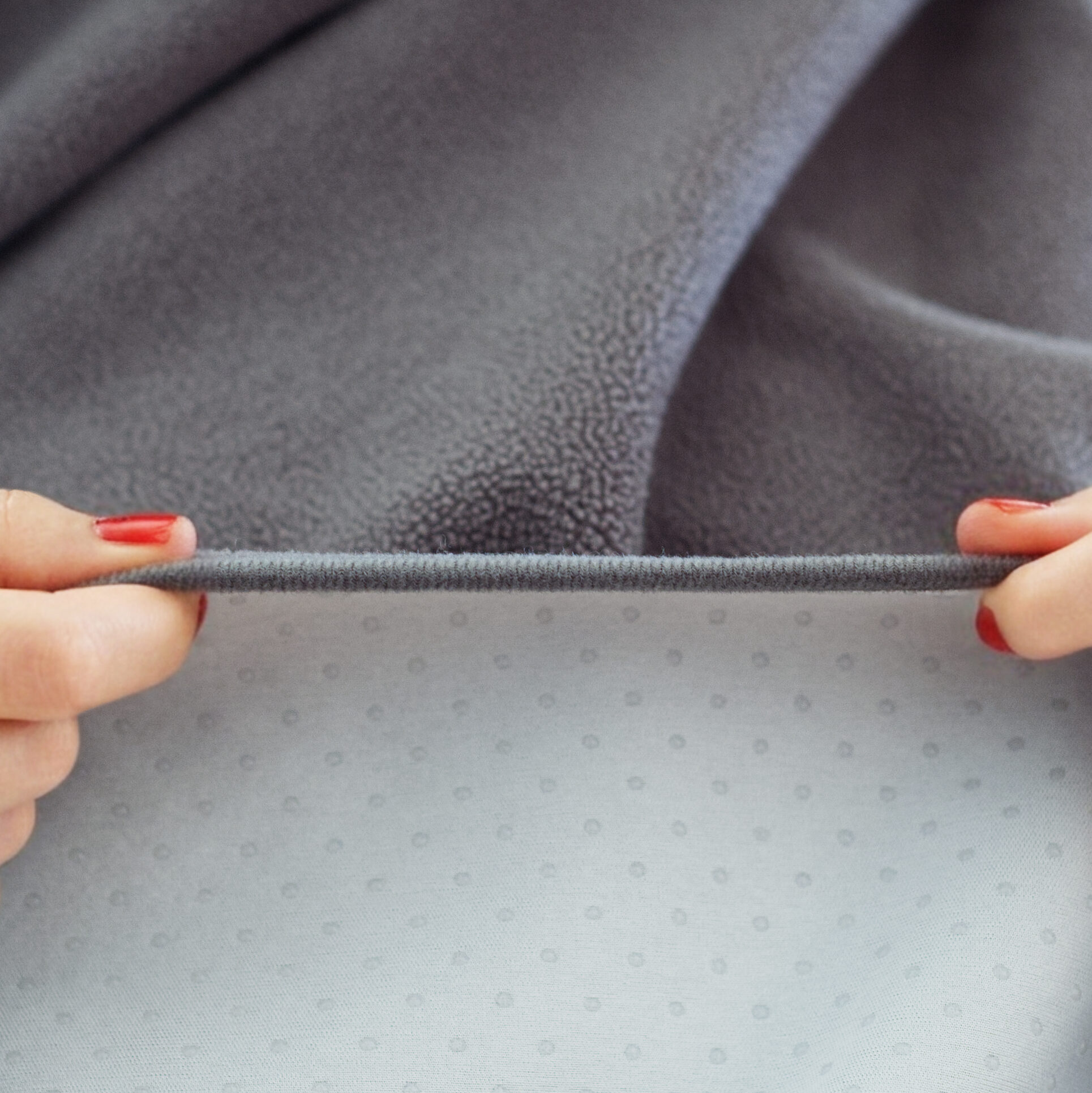 GripMe waterproof blanket shown edge on, with soft polar fleece shown on the upper half and silicon dots lining the underside fabric.