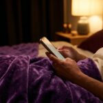 Phone glowing on a bed at night where woman is in bed and has a beautiful purple waterproof throw on her from Banana Passion , about to send a message